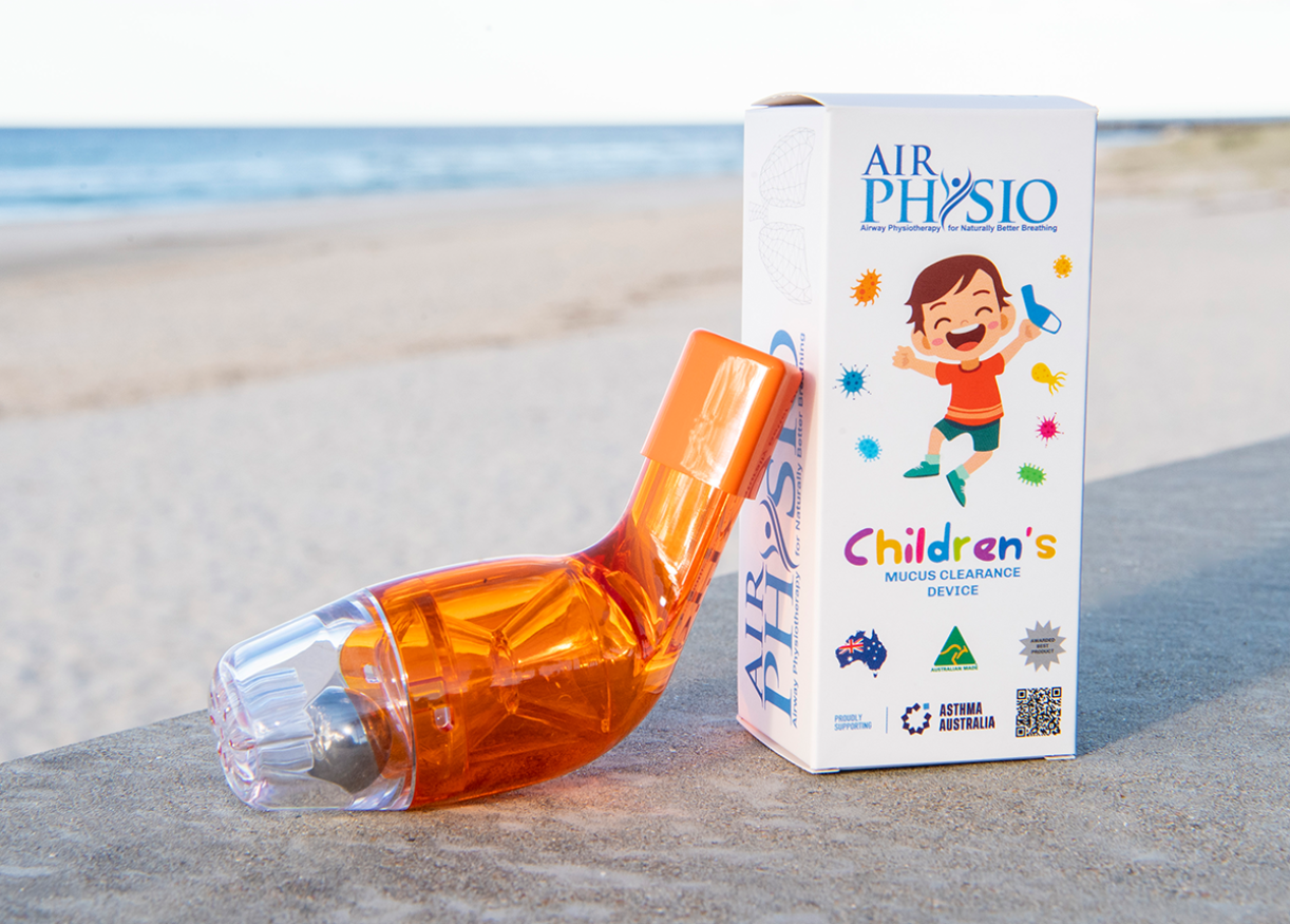 Hand holding orange and clear AirPhysio Children's device outdoors