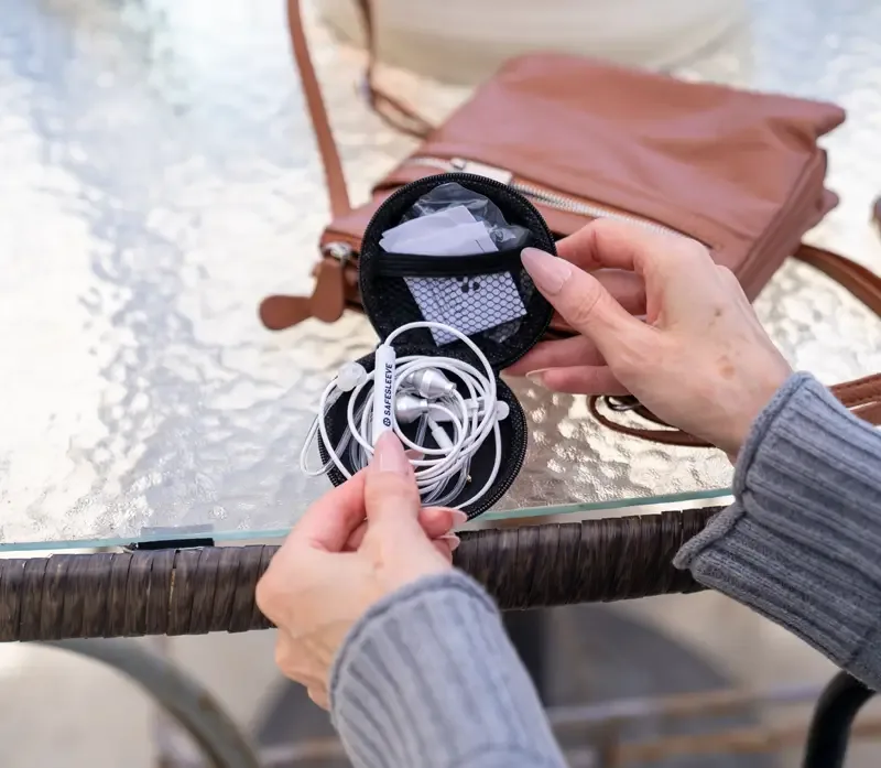 Carrying case with SafeSleeve earphones beside a purse