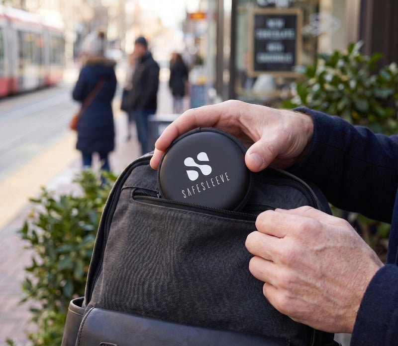 SafeSleeve carrying case being placed in a backpack pocket outdoors