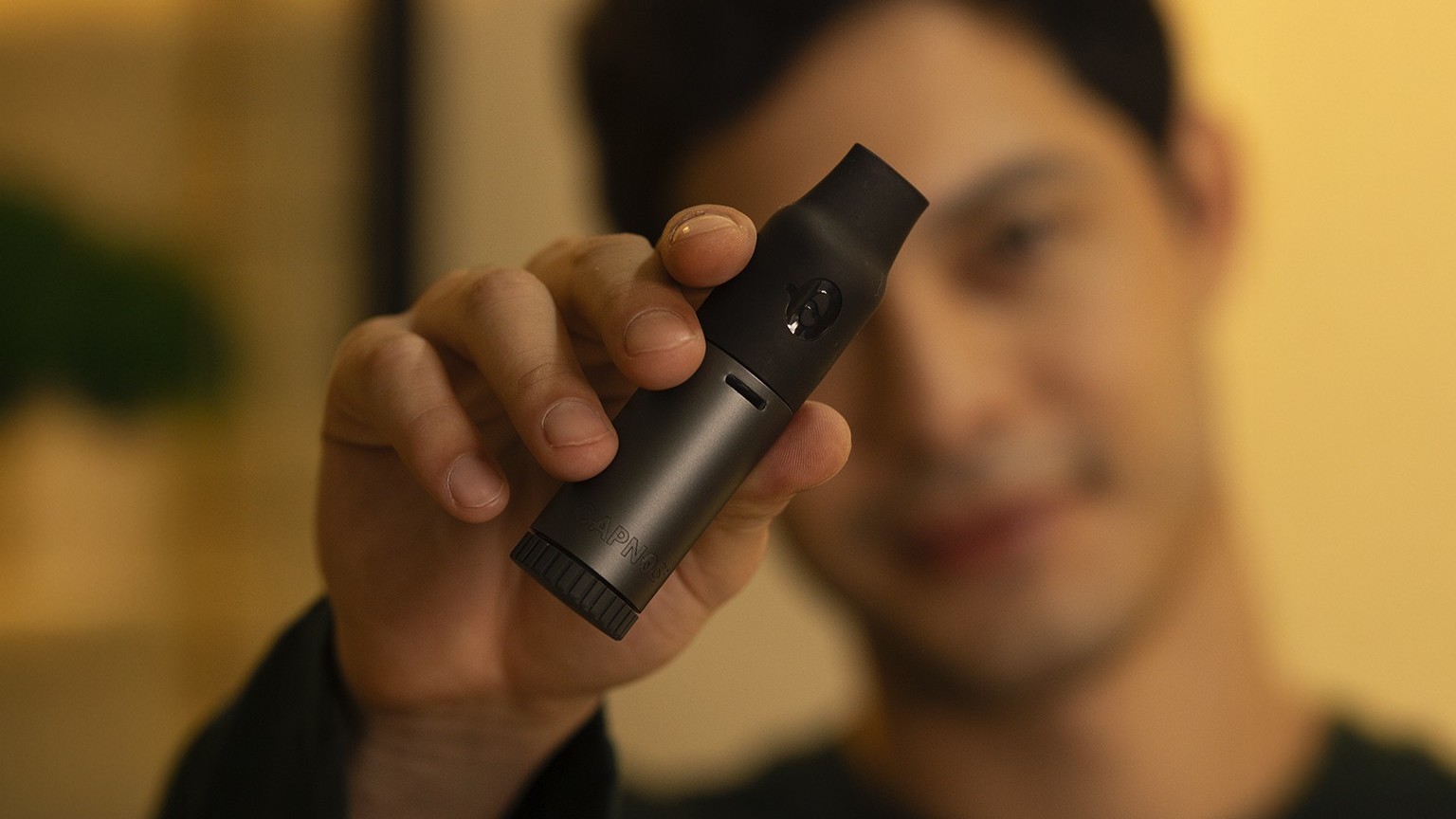 Close-up of a person holding the Capnos Legura device in a casual setting