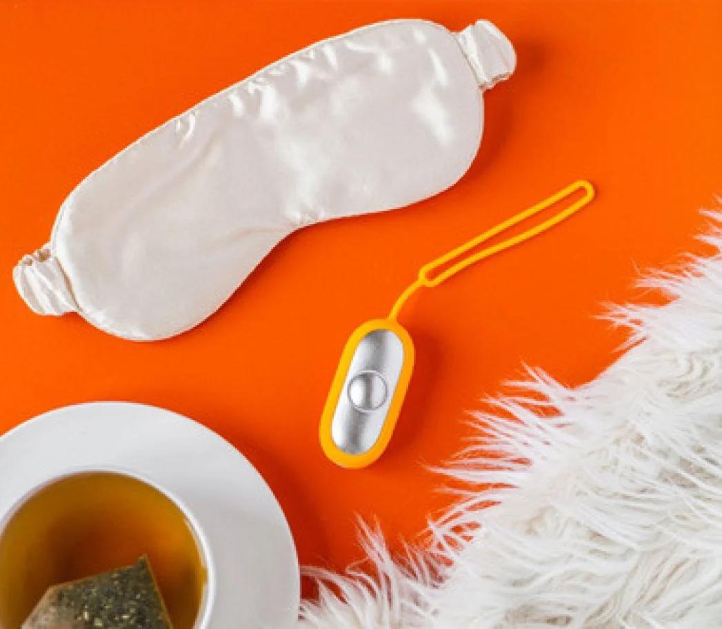 Chill Pill device placed next to a sleep mask and tea