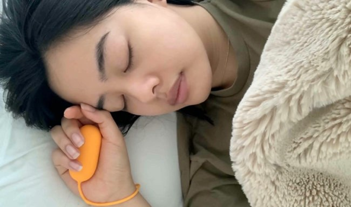 Person sleeping in bed while holding the Chill Pill device