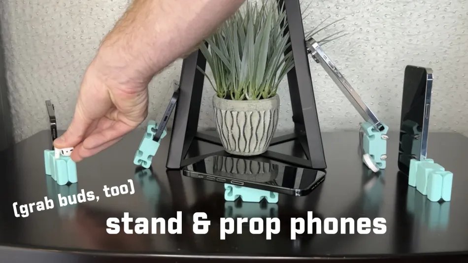 Person using CordBrick to prop up phones and hold earbuds on a table
