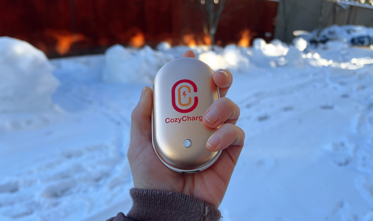 Person holding CozyCharge outdoors in snowy weather