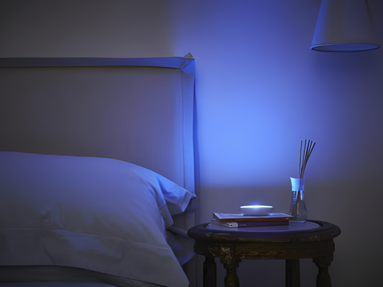 Dodow blue light on a bedside table in a dim bedroom