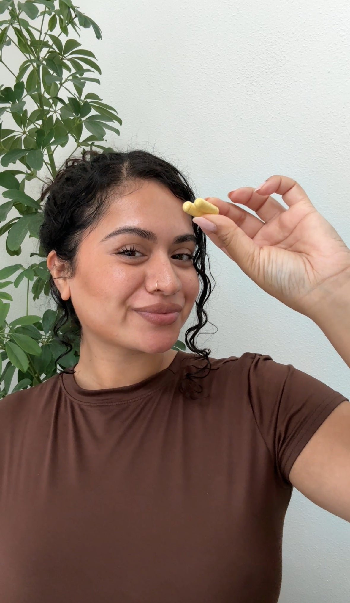 Person smiling and holding an Emma capsule between their fingers
