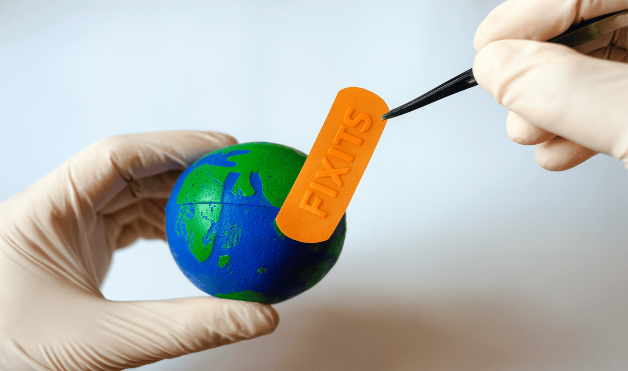 Gloved hands applying an orange FixIts stick to a small globe using tweezers