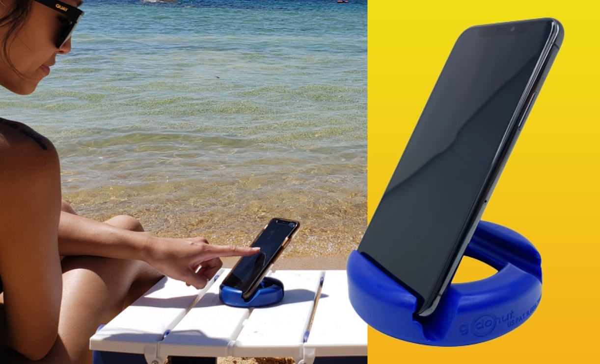 GoDonut stand holding a smartphone on a table by the beach