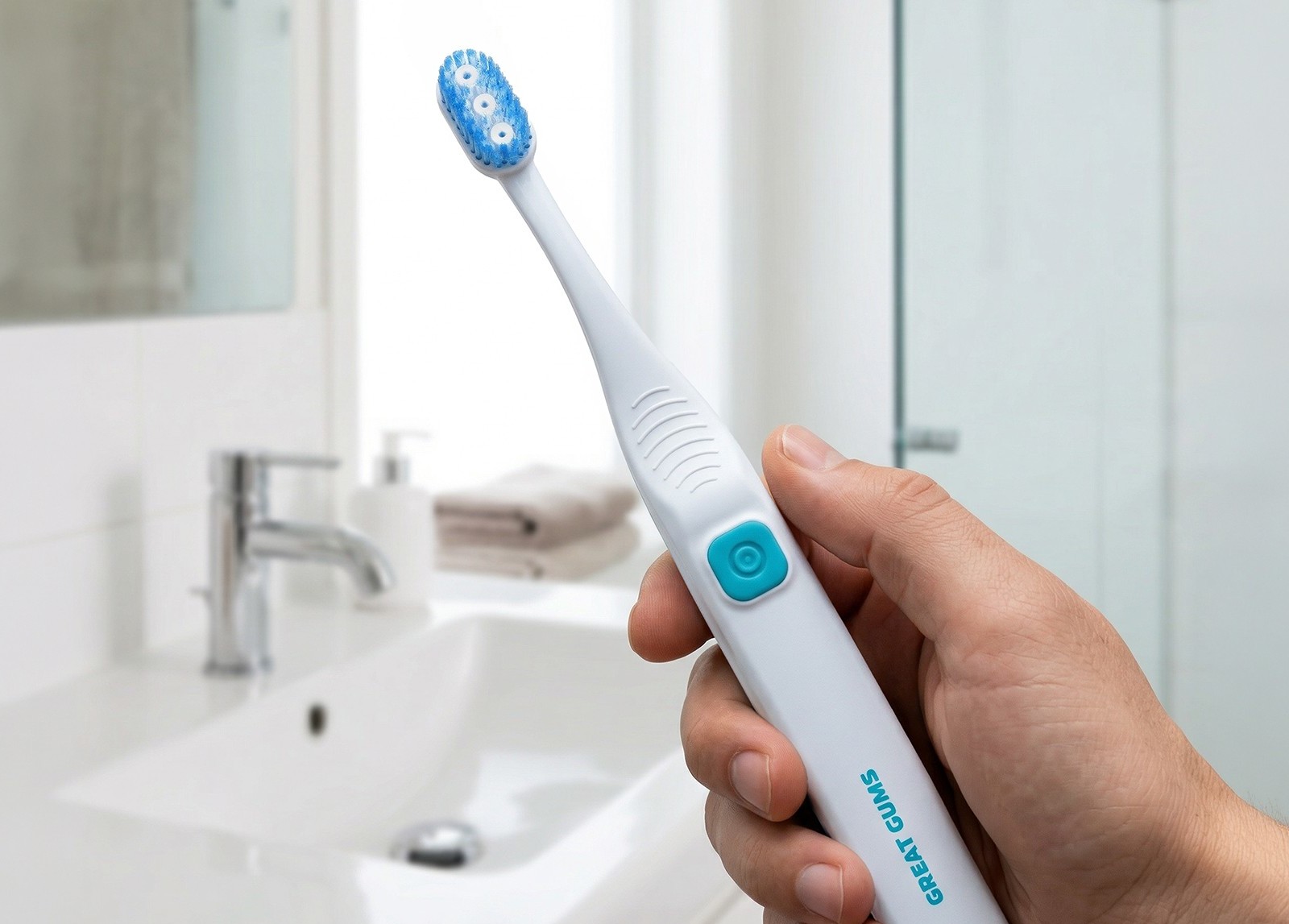 A person holding the Great Gums toothbrush in a bathroom setting