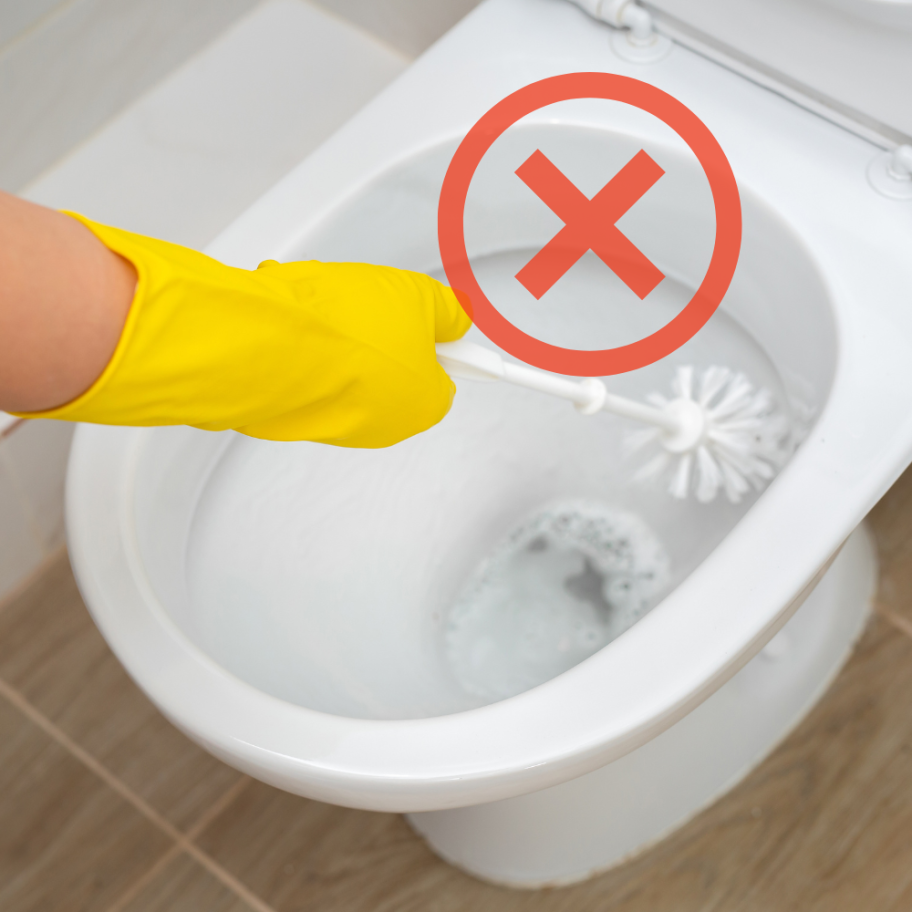 Person with gloved hand using a toilet brush inside a toilet bowl with a red X overlay