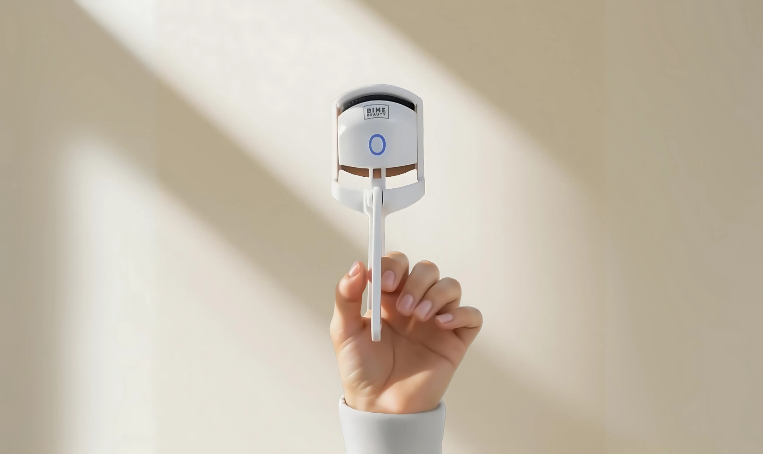 Hand holding the Bime Beauty Heated Eyelash Curler