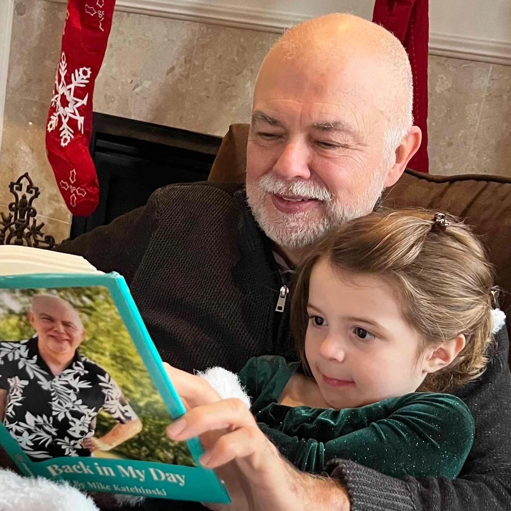 An older man and a young girl sitting together reading a personalized memory book