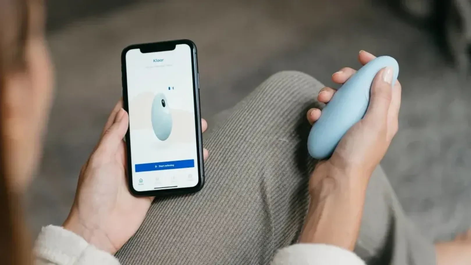 Person holding Moonbird and smartphone displaying app while sitting