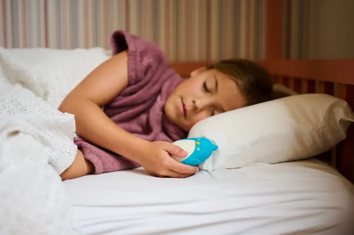 Child lying in bed holding Moonbuddy while sleeping