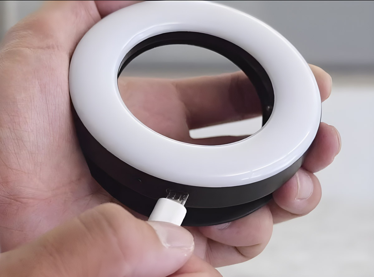 Close-up of a hand plugging a charging cable into a ring light