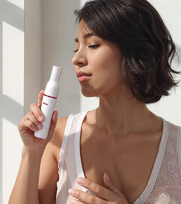 Person holding the Pluxy device near their face in a bright room