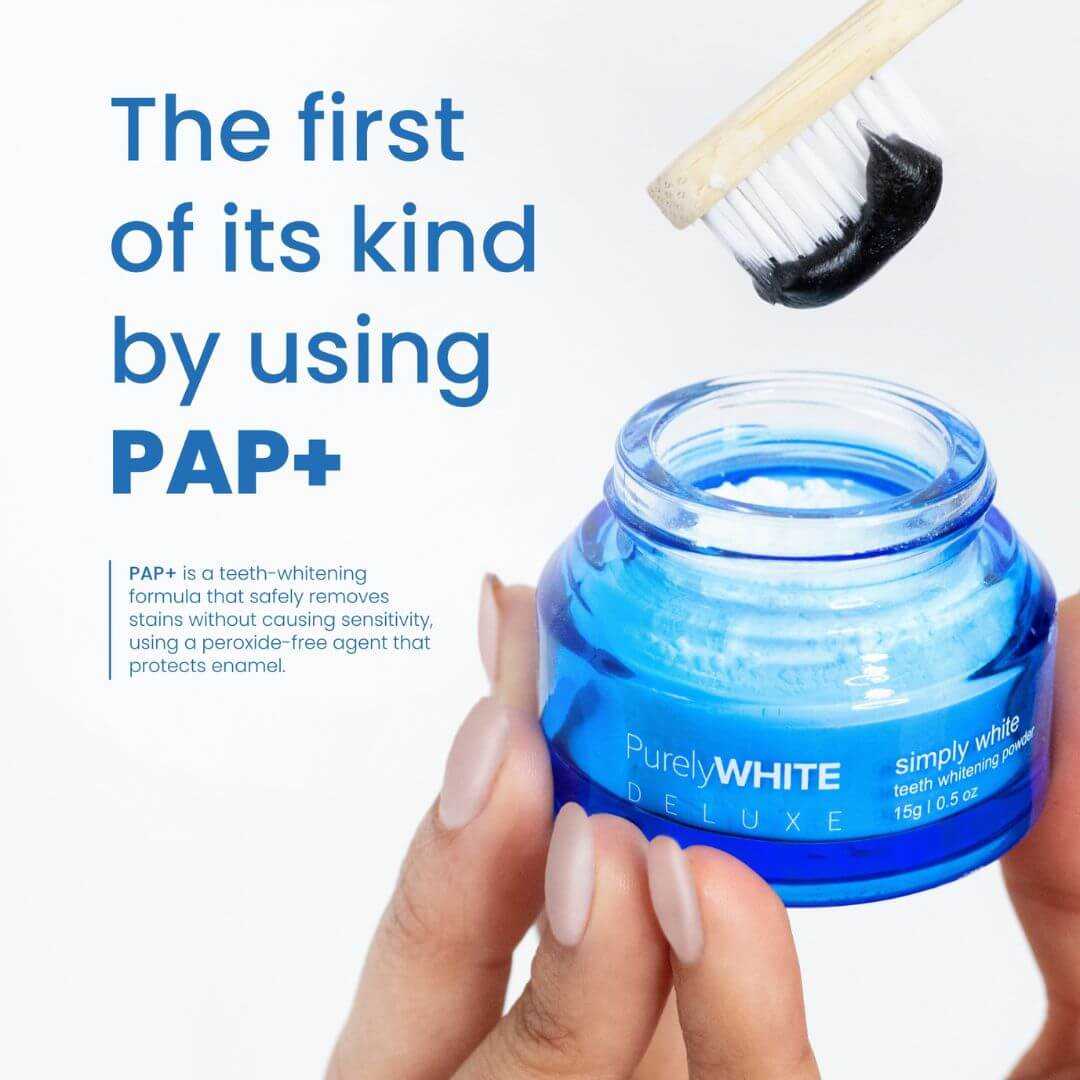 Hand holding toothbrush with powder above an open jar of PurelyWHITE Deluxe whitening powder