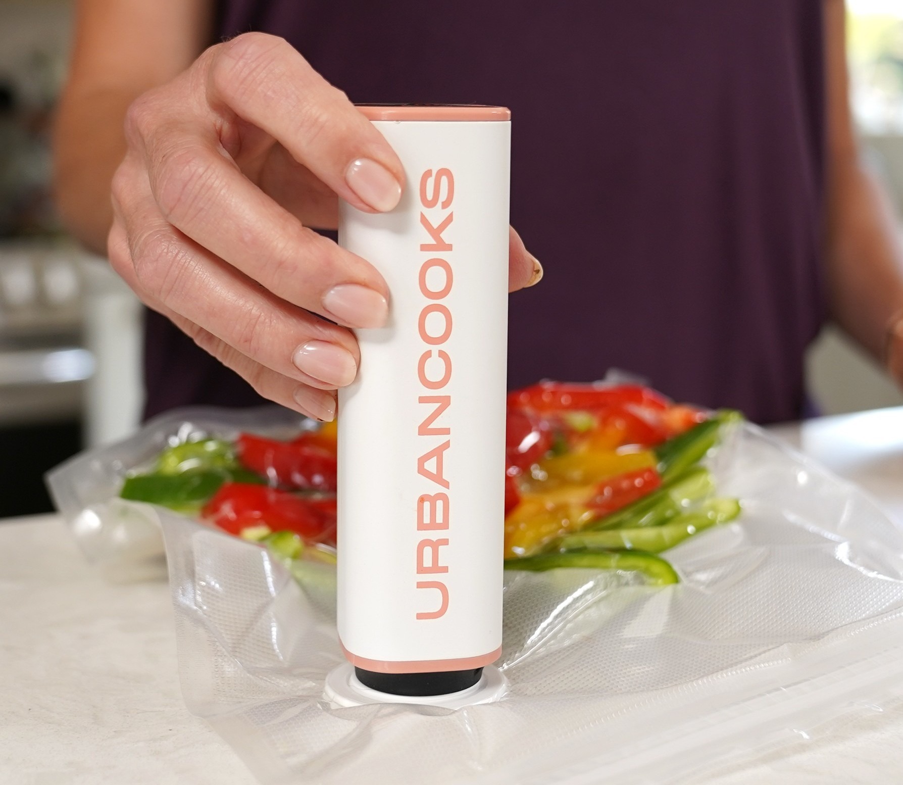 Close-up of a hand holding the SealPro vacuum sealer over a vacuum-sealed bag