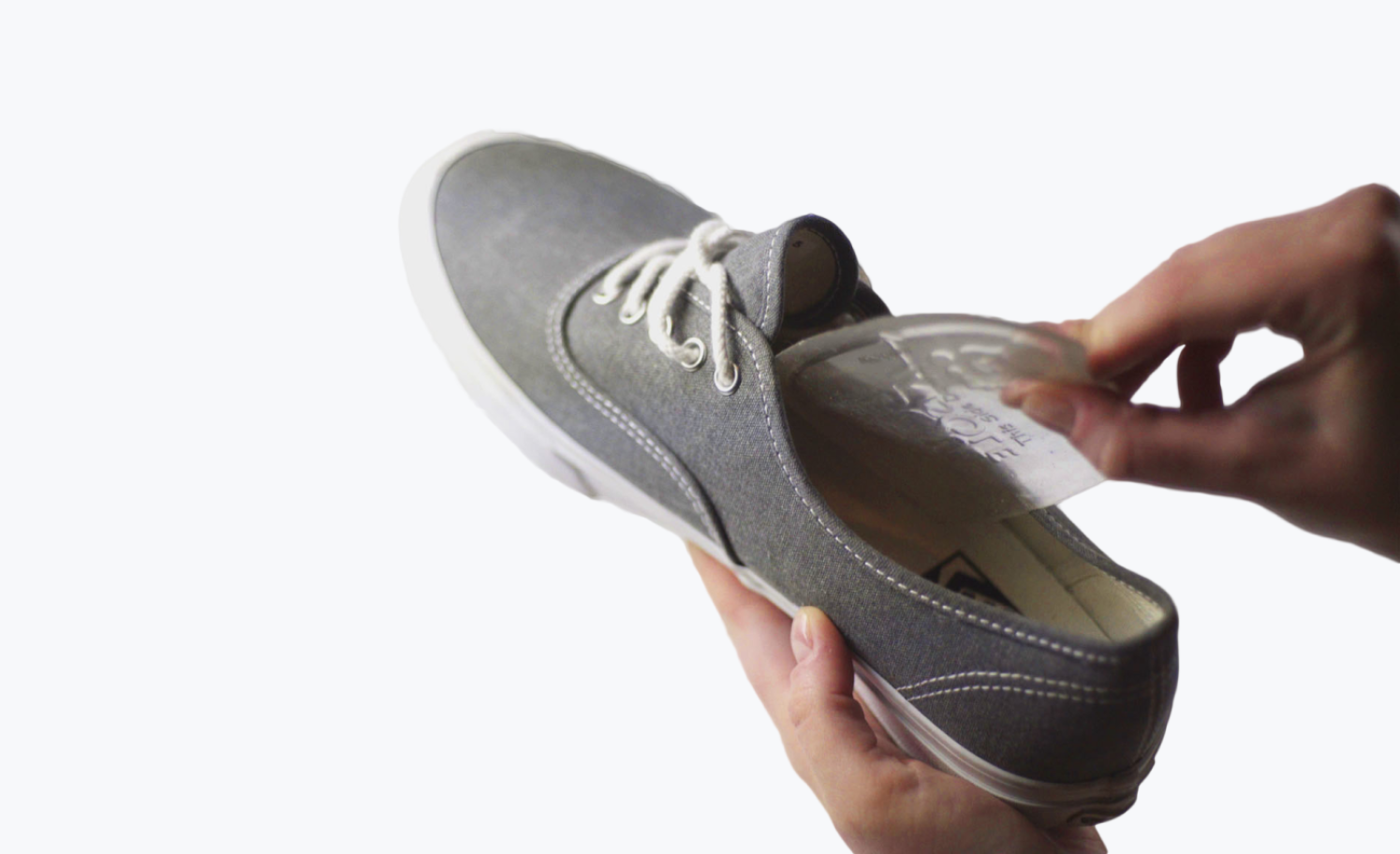Person placing a clear insole into a gray sneaker