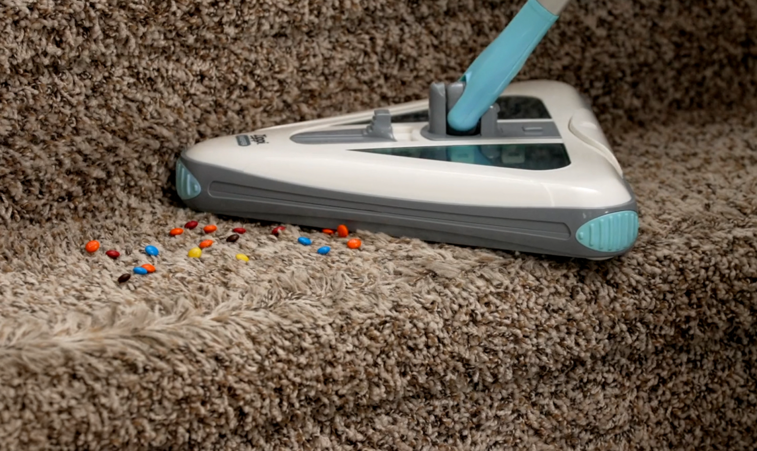 Sweeper picking up small colorful debris on a carpeted staircase